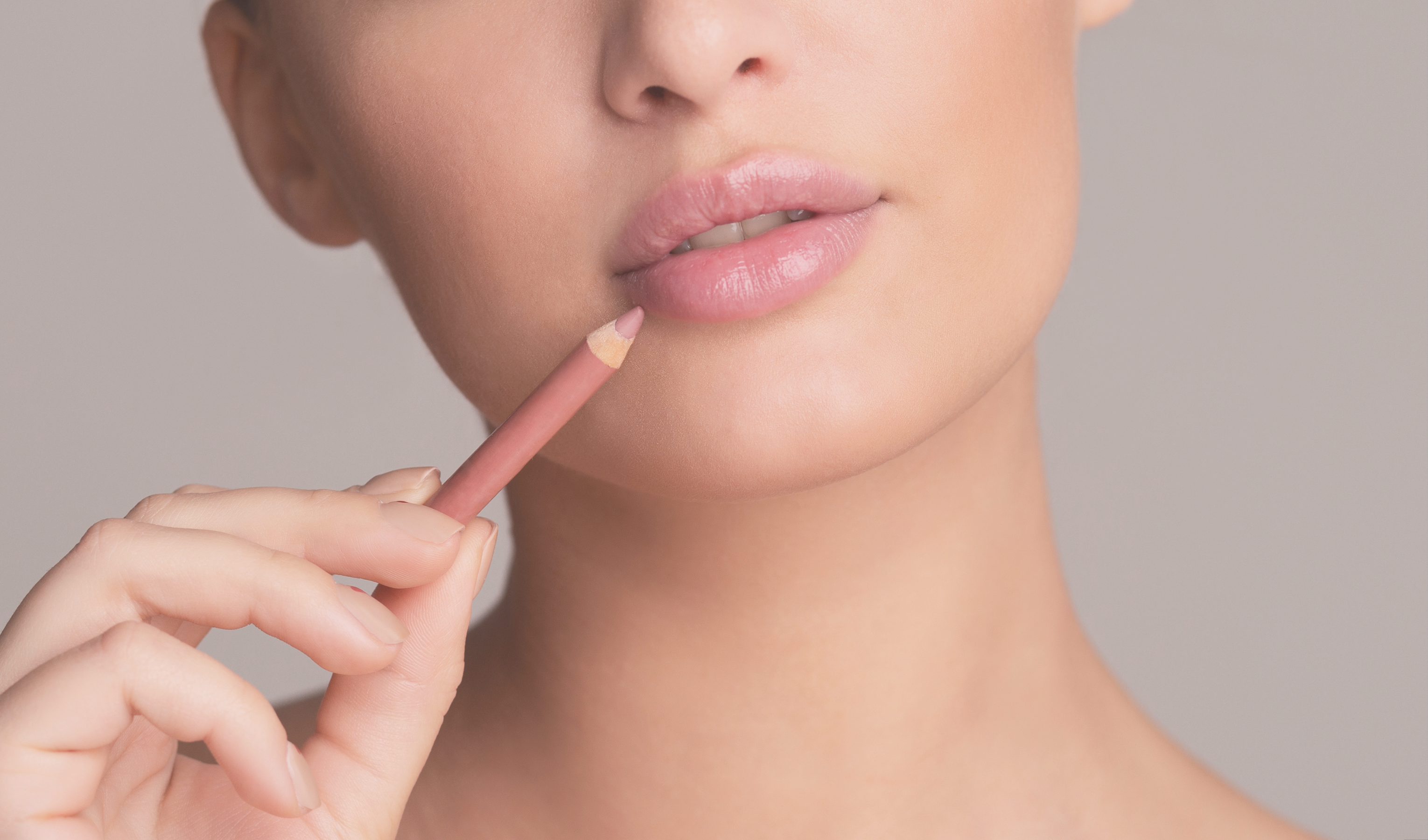 woman holding a pink lipliner next to her lips