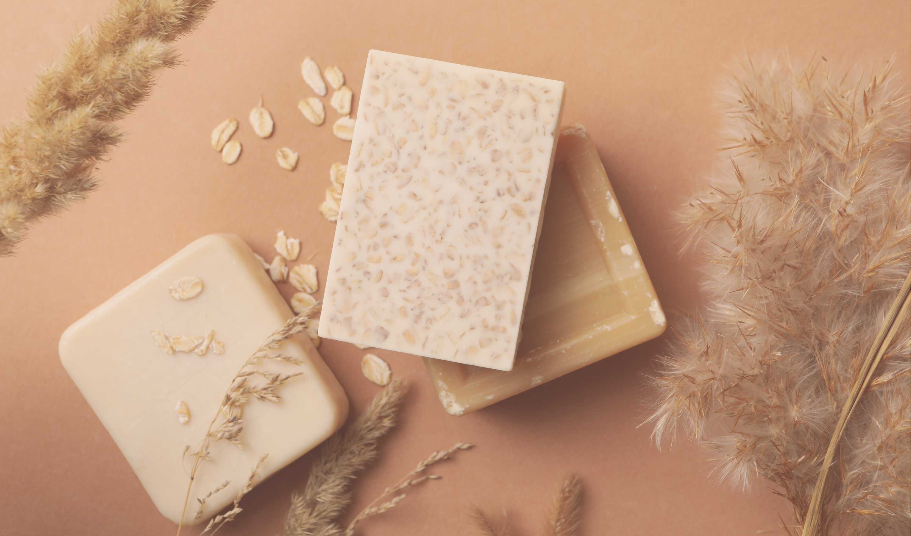 three natural soaps laid out on table with plants