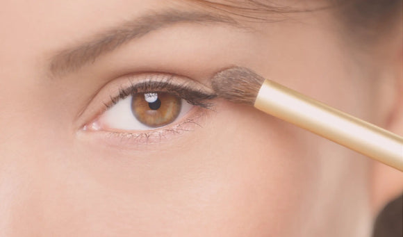 woman applying eye makeup with eyeshadow brush