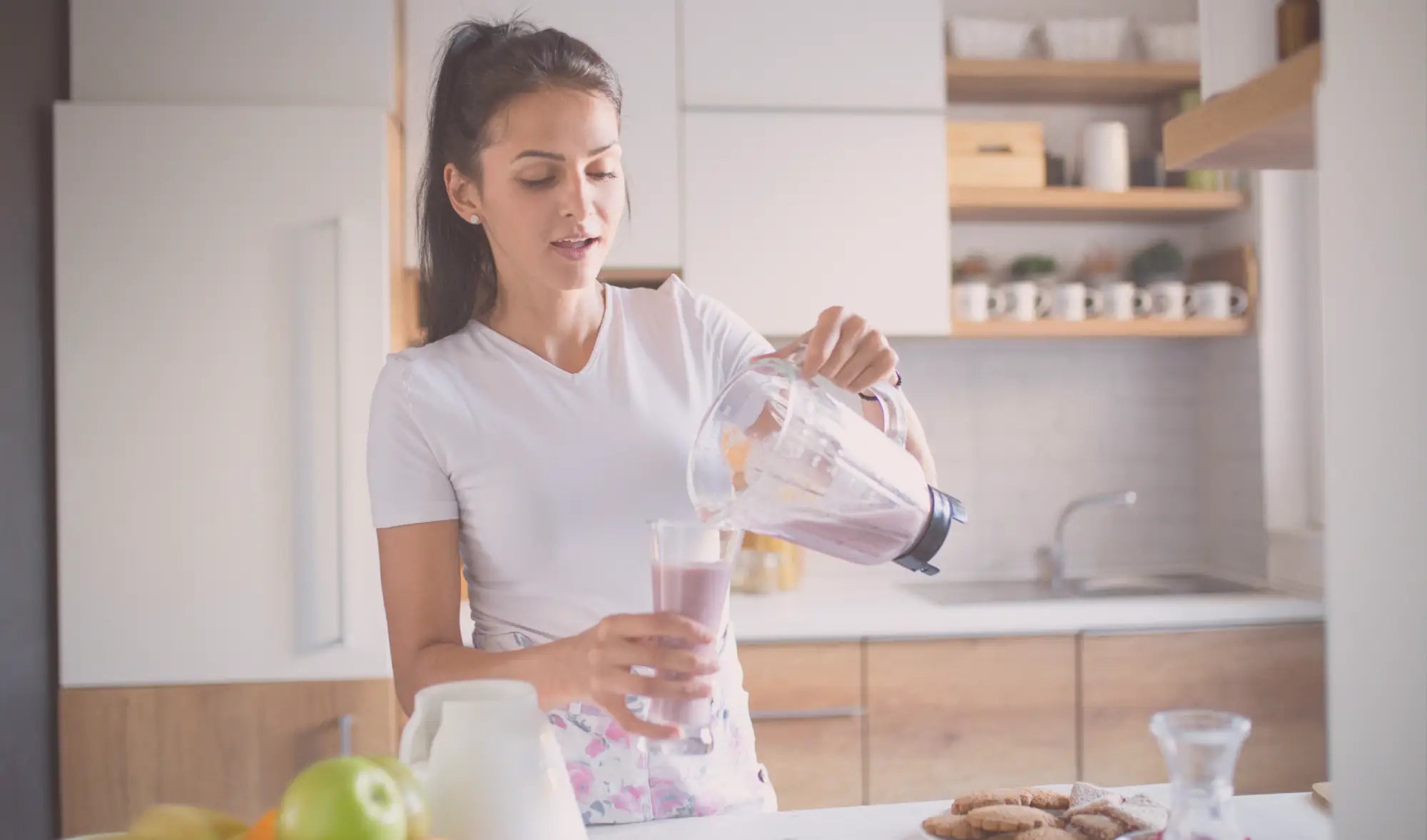 woman in kitchen pouring a smoothie from a blender