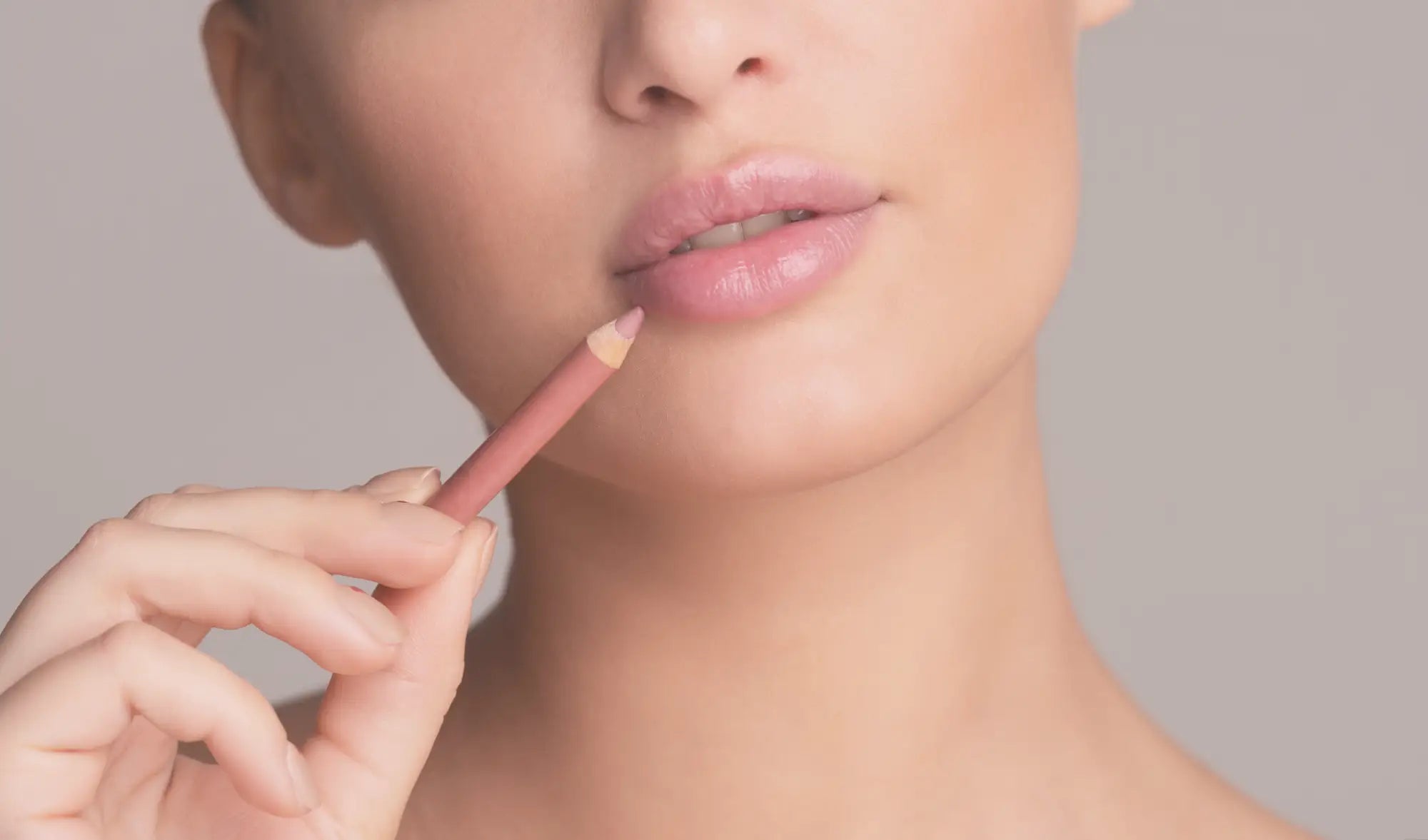 woman holding a pink lipliner next to her lips