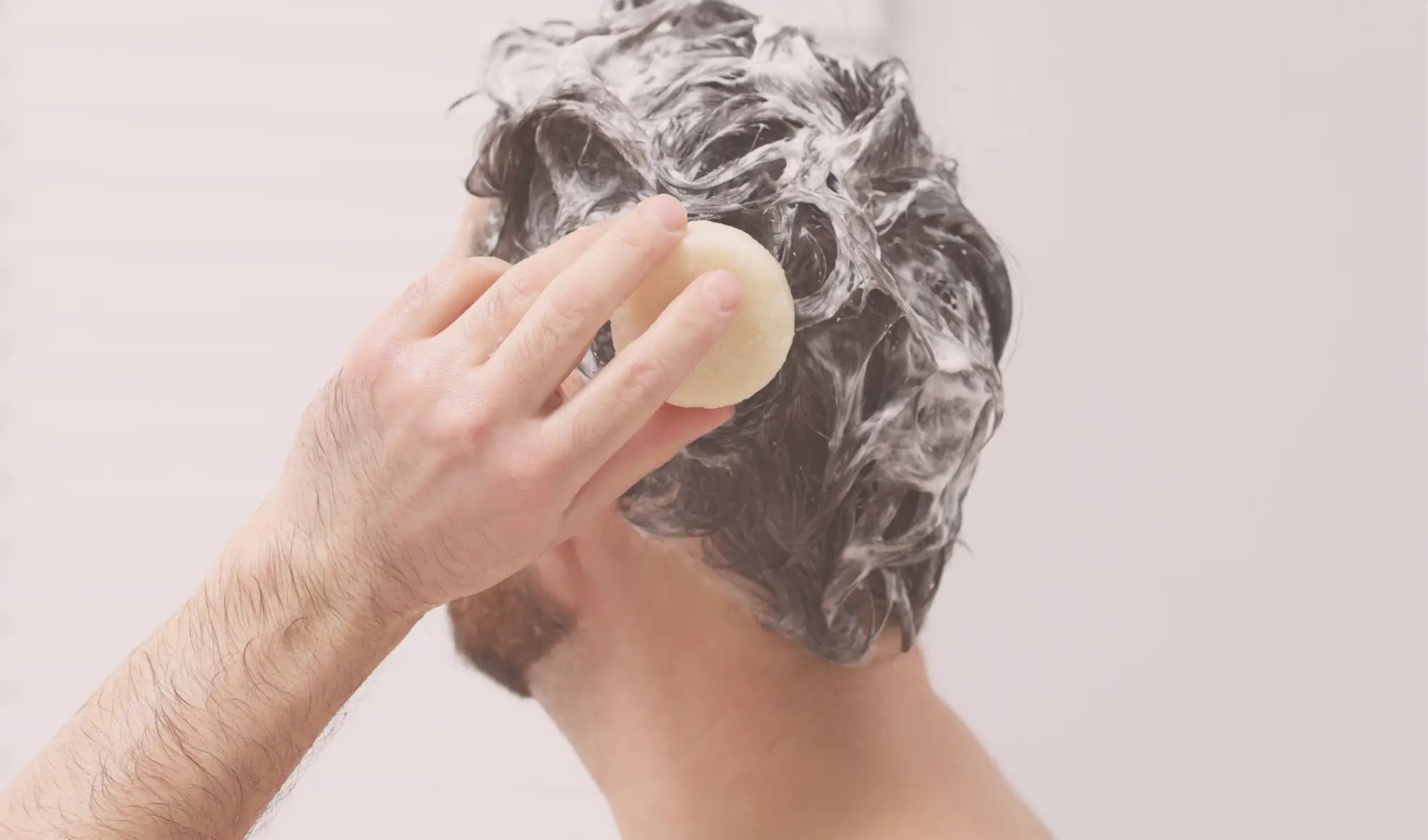 man lathering his hair with natural bar soap shampoo