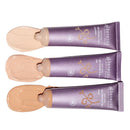 Three purple tubes of foundation or BB cream with beige product swatches beside them.
