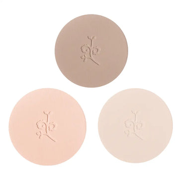 Three circular pressed powder compacts in different nude and beige tones with embossed floral designs.