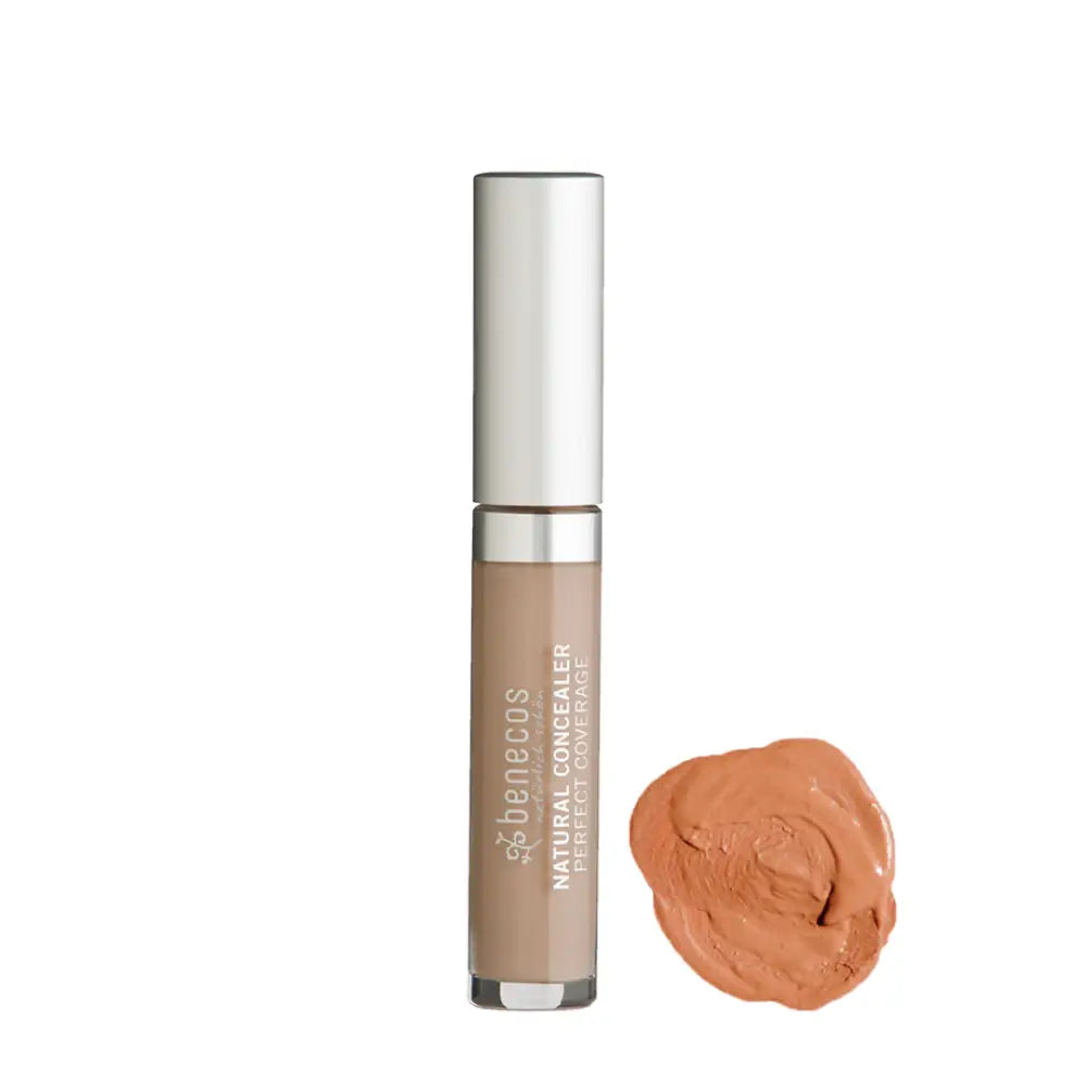 Silver-capped cosmetic concealer tube with a swatch of peachy-colored product beside it.