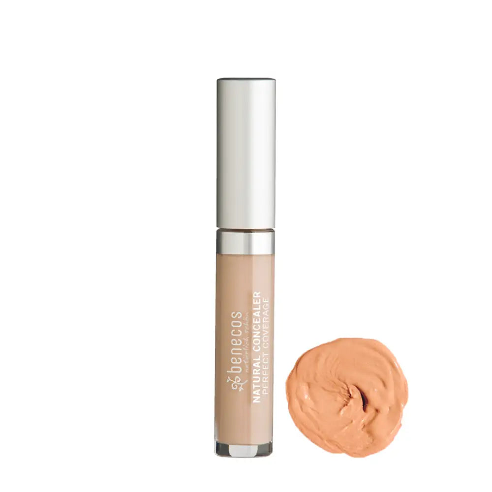 Silver-capped concealer tube with a peach-colored product sample beside it.