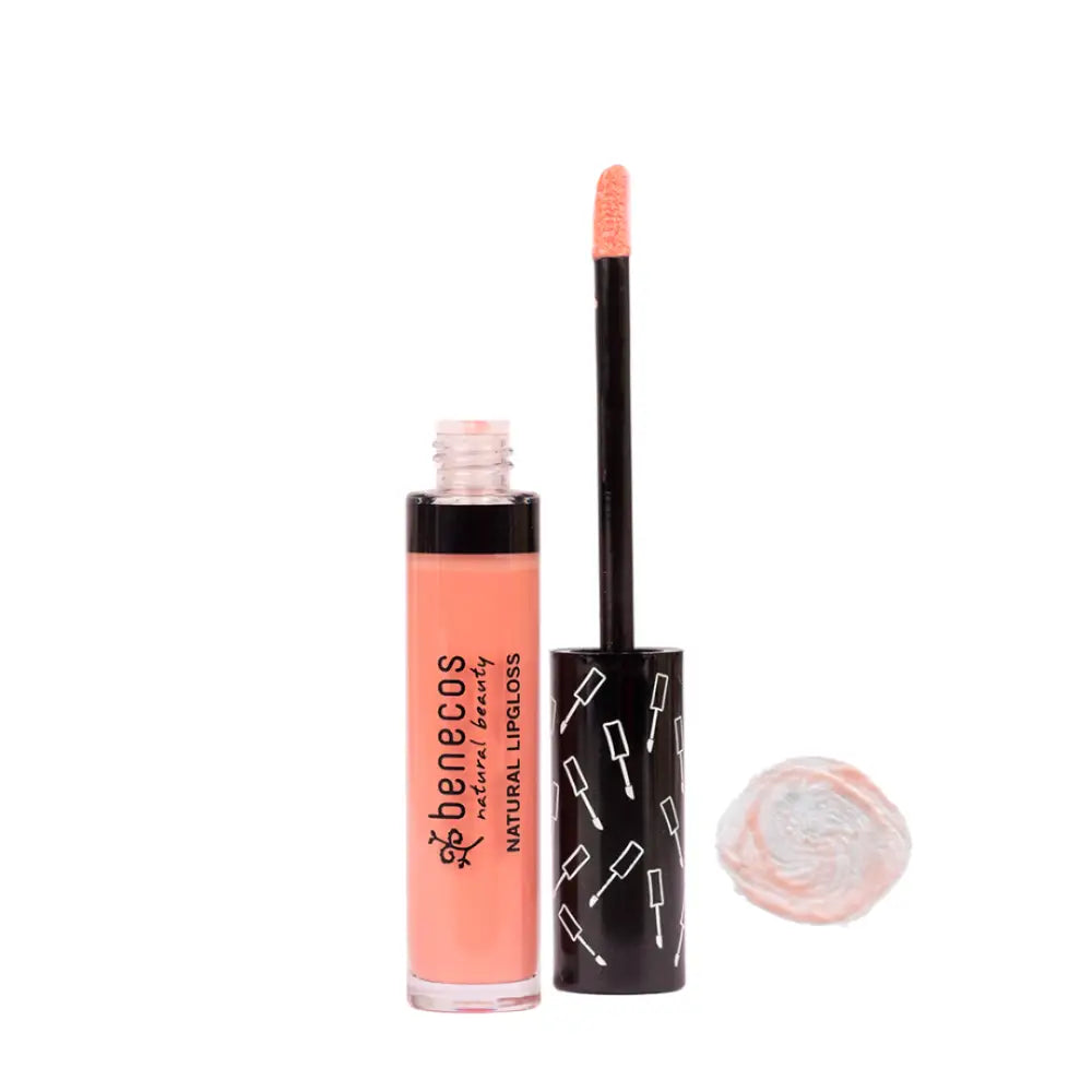 Peach-colored lip gloss in a black tube with small white pattern designs.