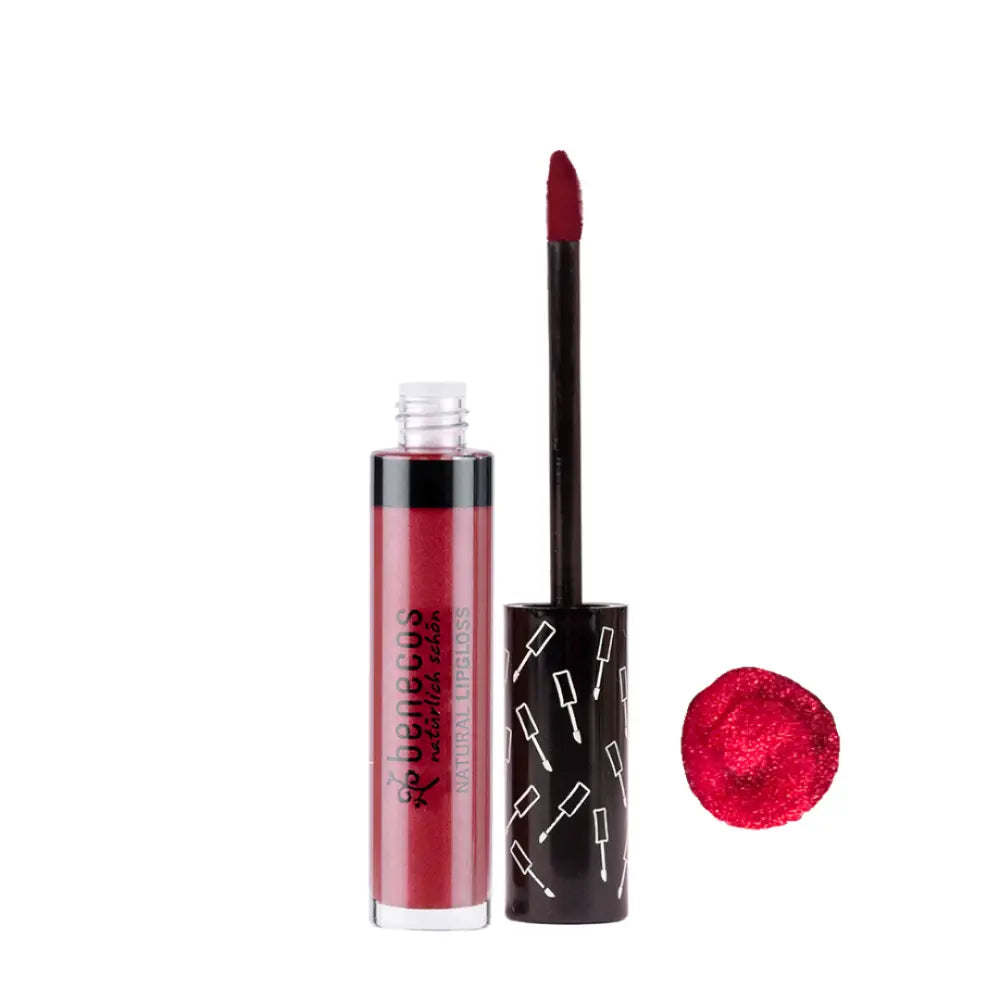 Red liquid lipstick with a black applicator wand and decorative pattern on the tube.