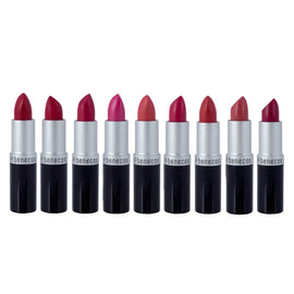 Nine Benecos brand lipsticks in various shades of red and pink arranged in a row.