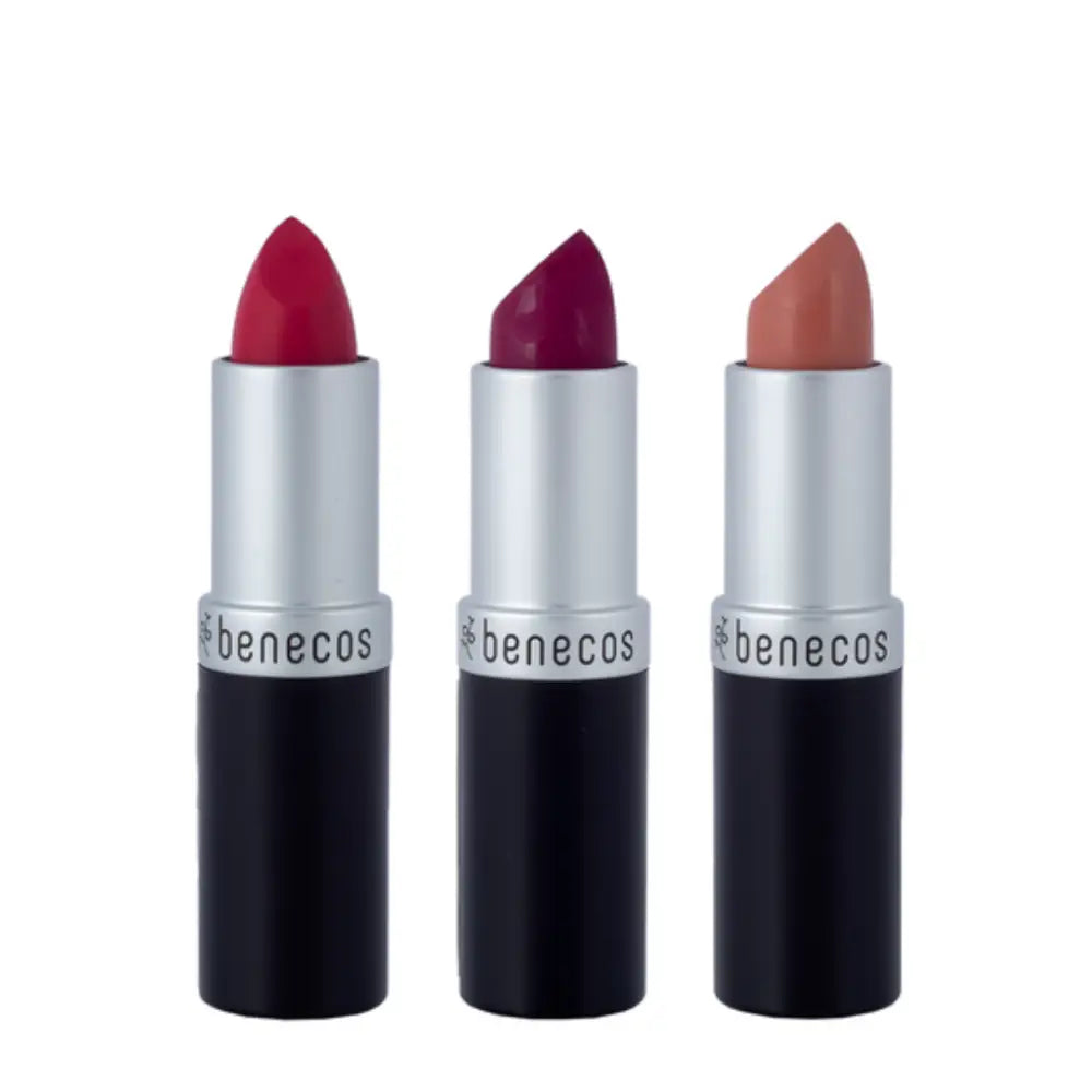 Three Benecos lipsticks in silver and black tubes showing red, burgundy, and nude shades.