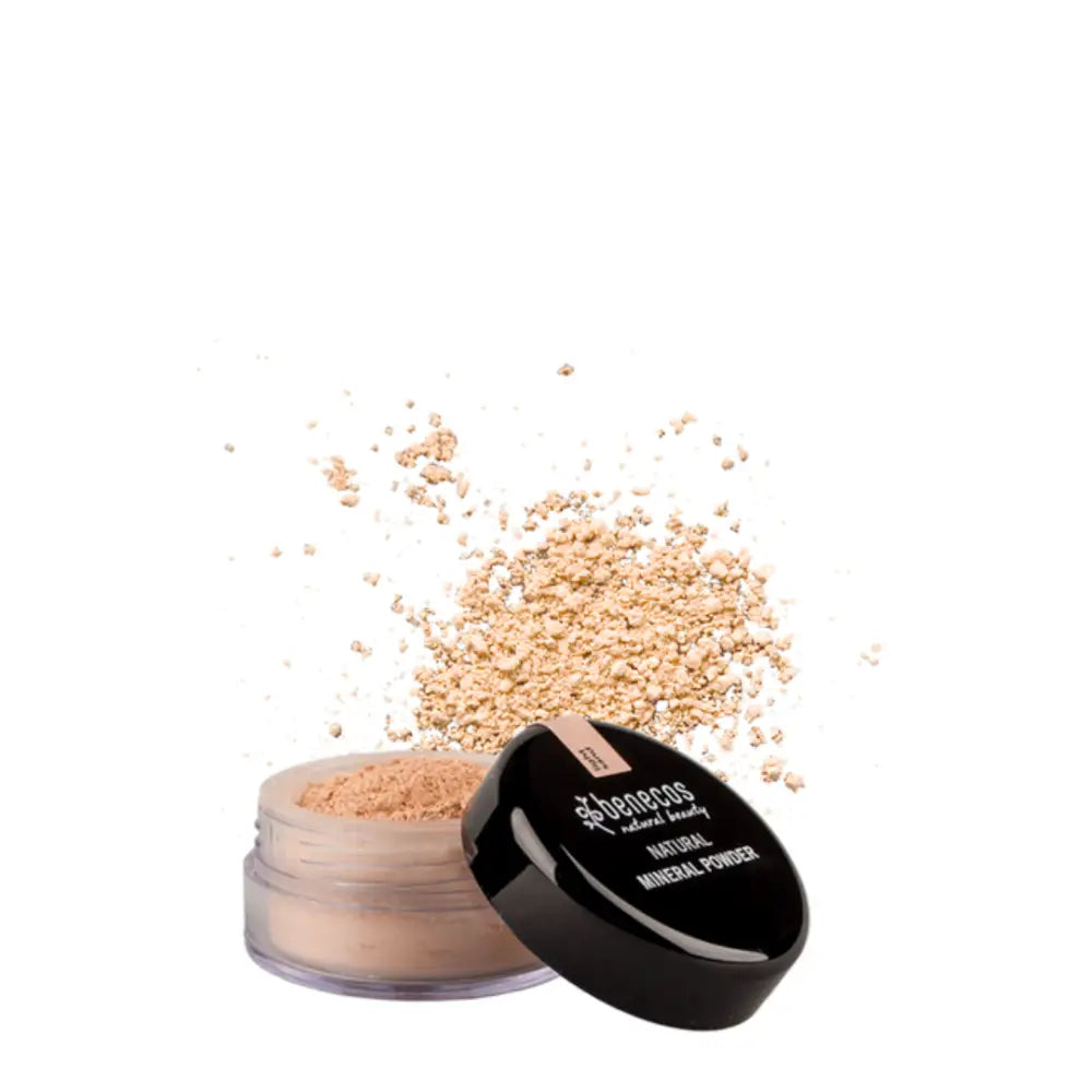 Open jar of loose mineral makeup powder with scattered beige powder beside it.