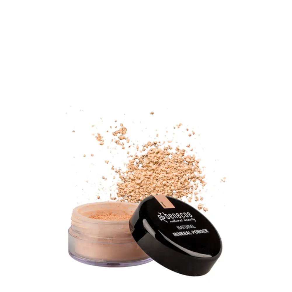 Open container of loose mineral powder makeup with scattered powder around it.