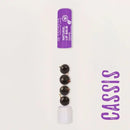 Purple lip balm tube with dark spherical candies or treats below it.