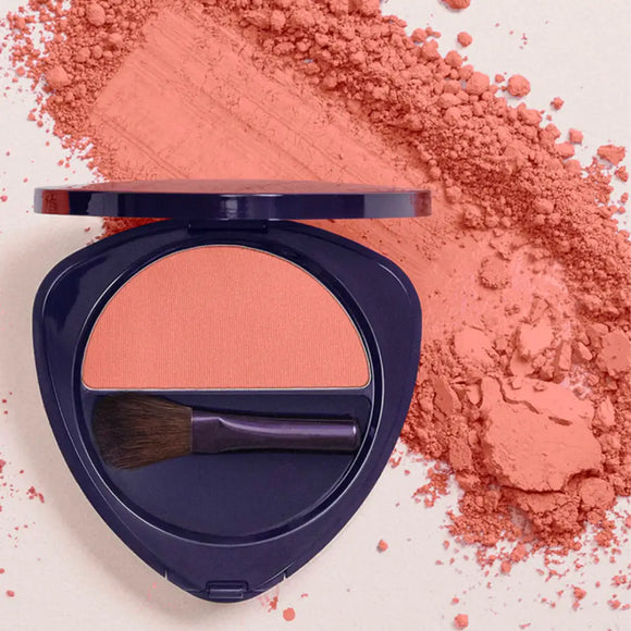 Navy blue compact powder case with coral-colored blush and a makeup brush.