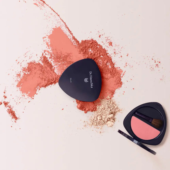 Coral-colored makeup powder and compact with spilled powder residue.