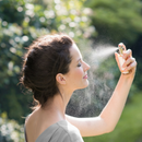 Woman spraying face mist.
