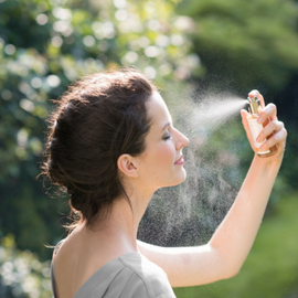 Woman spraying face mist.