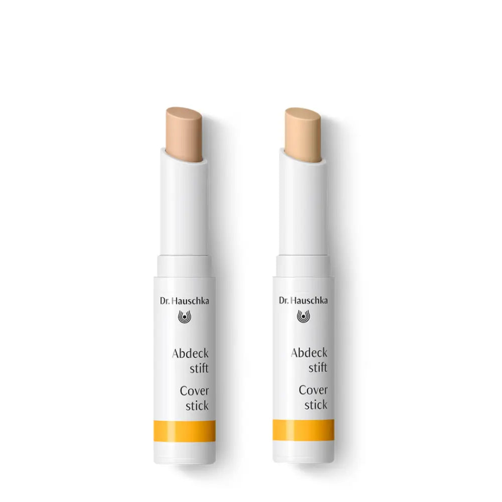 Two white Dr. Hauschka cover stick concealers with beige tips.