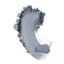Smeared silvery-grey eyeshadow powder with scattered particles.
