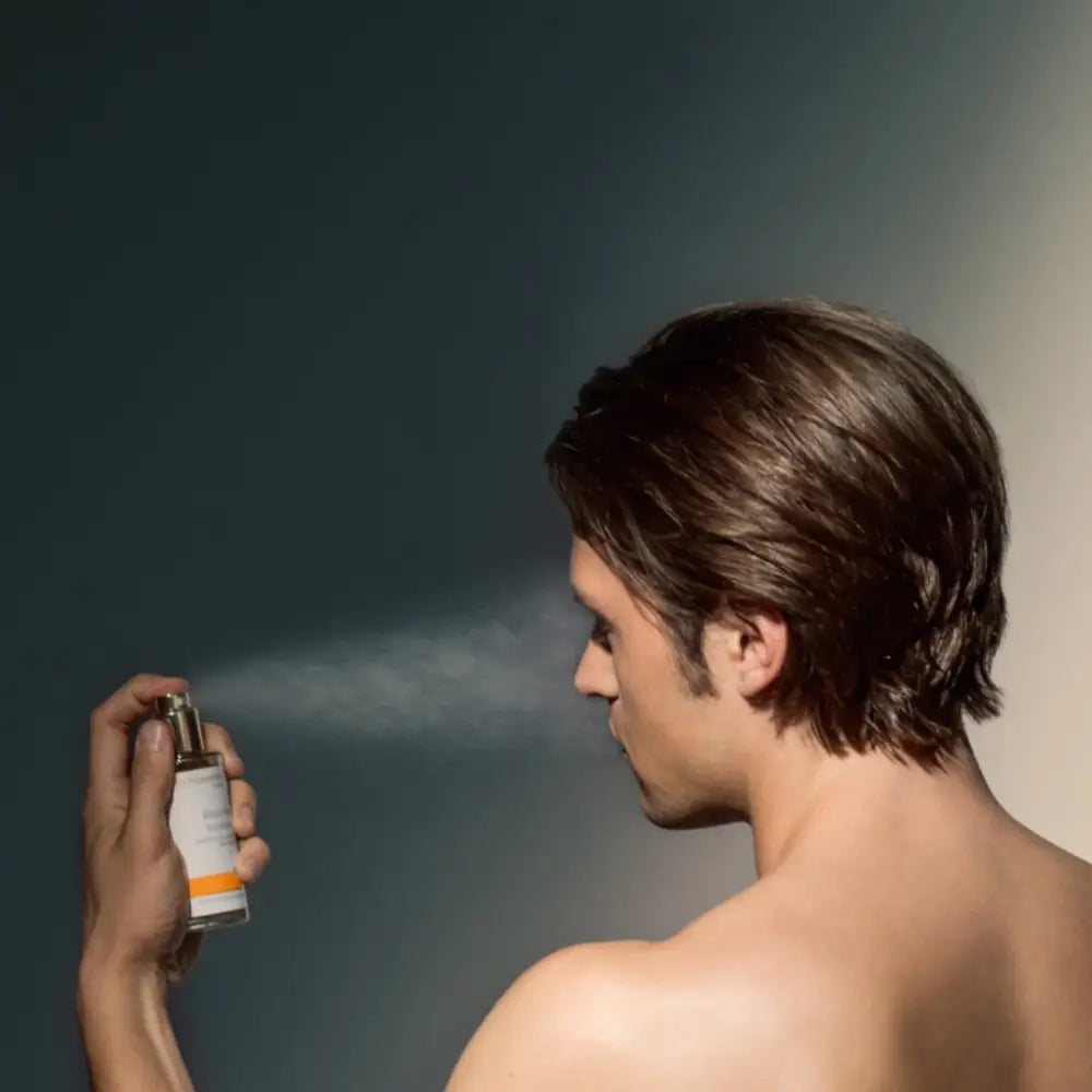 A person spraying deodorant or body spray in front of their face.