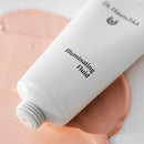 White cosmetic tube containing illuminating fluid with product dispensed in a peachy tone.