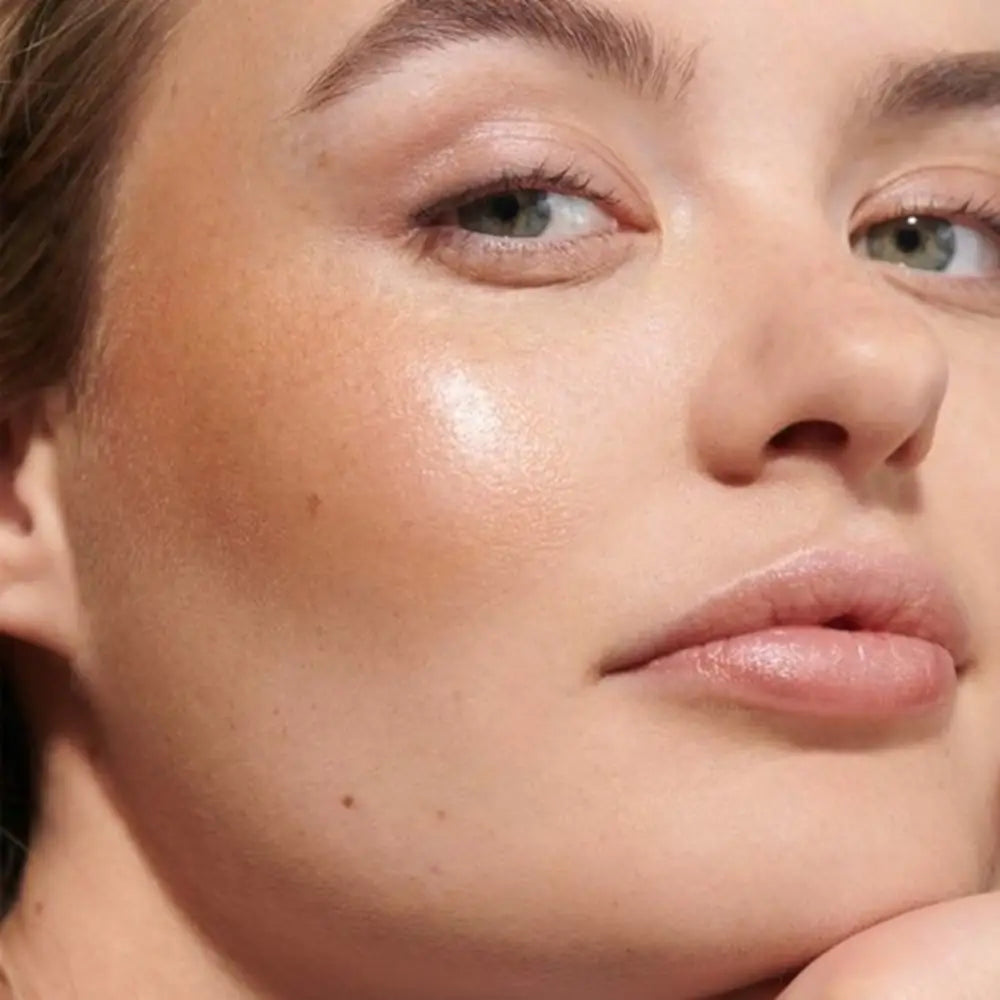 Close-up portrait showing glowing skin, glossy lips and defined eyebrows.