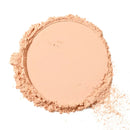 Pressed powder makeup compact in a light peachy-beige shade with scattered loose powder around the edges.