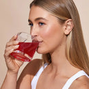 A glass of red-colored beverage being sipped.