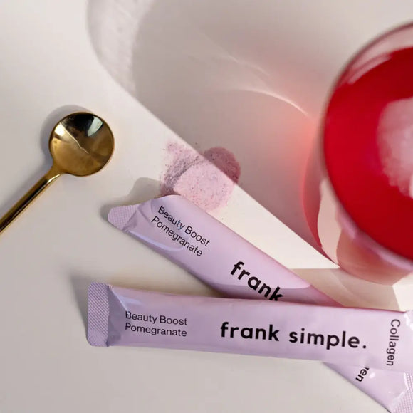 Frank Simple beauty boost pomegranate packets alongside a gold spoon.