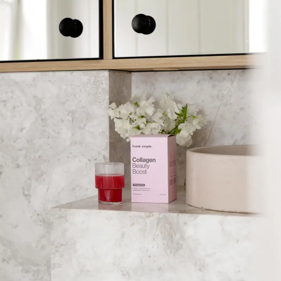 Pink box of collagen peptide powder with a red drink beside it.