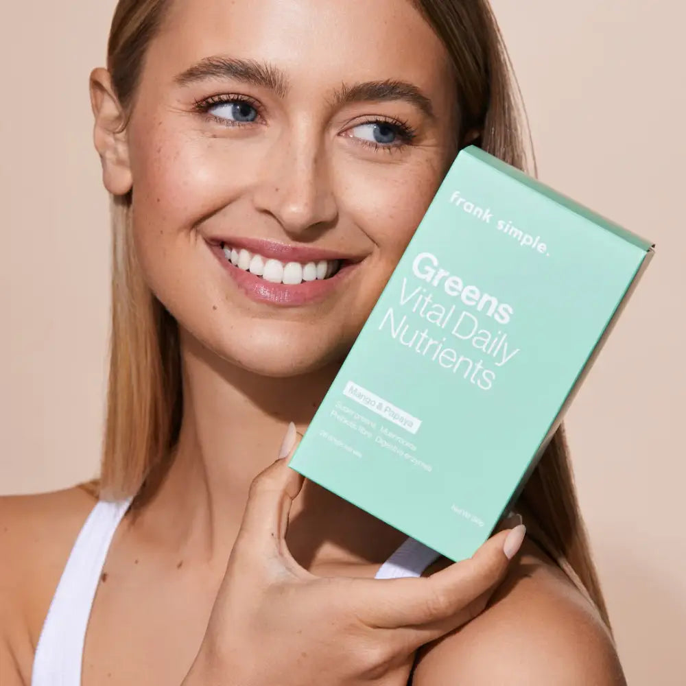 A mint green supplement box being held up against a white background.