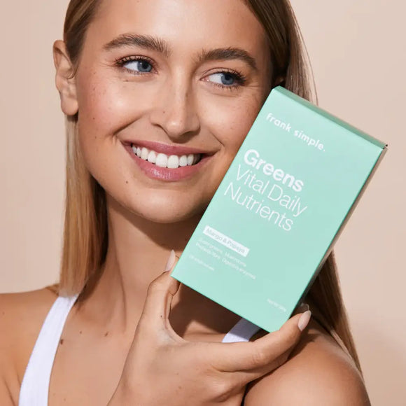 A mint green supplement box being held up against a white background.