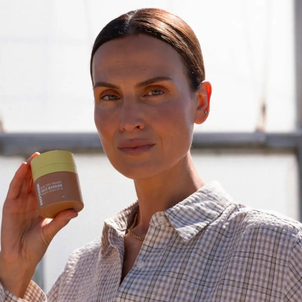 A golden-colored cosmetic or skincare product jar being held up.