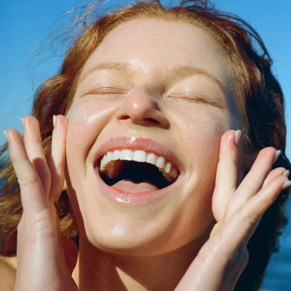 A joyful expression with hands framing the face and a wide, genuine laugh.