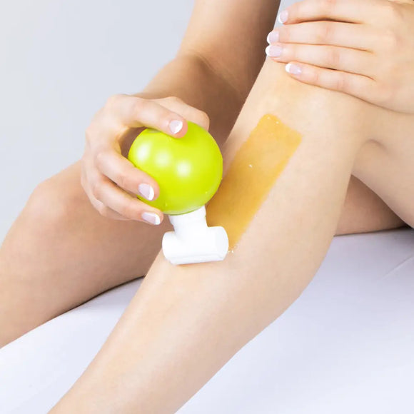 A waxing strip being applied to a leg while holding a green apple.