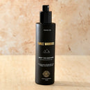 Black bottle of Three Warriors body tan aqua mist with gold lettering.