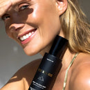 Black cosmetic spray bottle with gold text labeling.