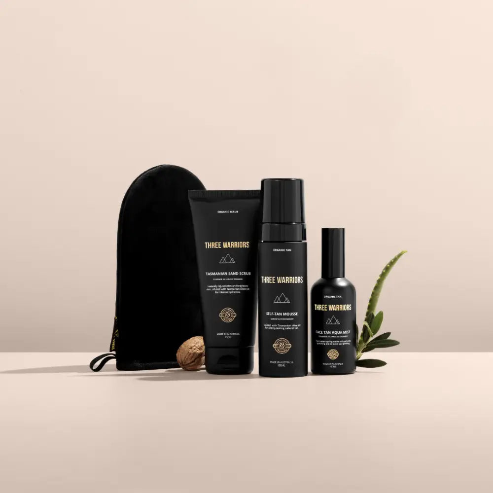 Collection of black skincare or beauty product bottles with gold accents alongside a black pouch and aloe plant.