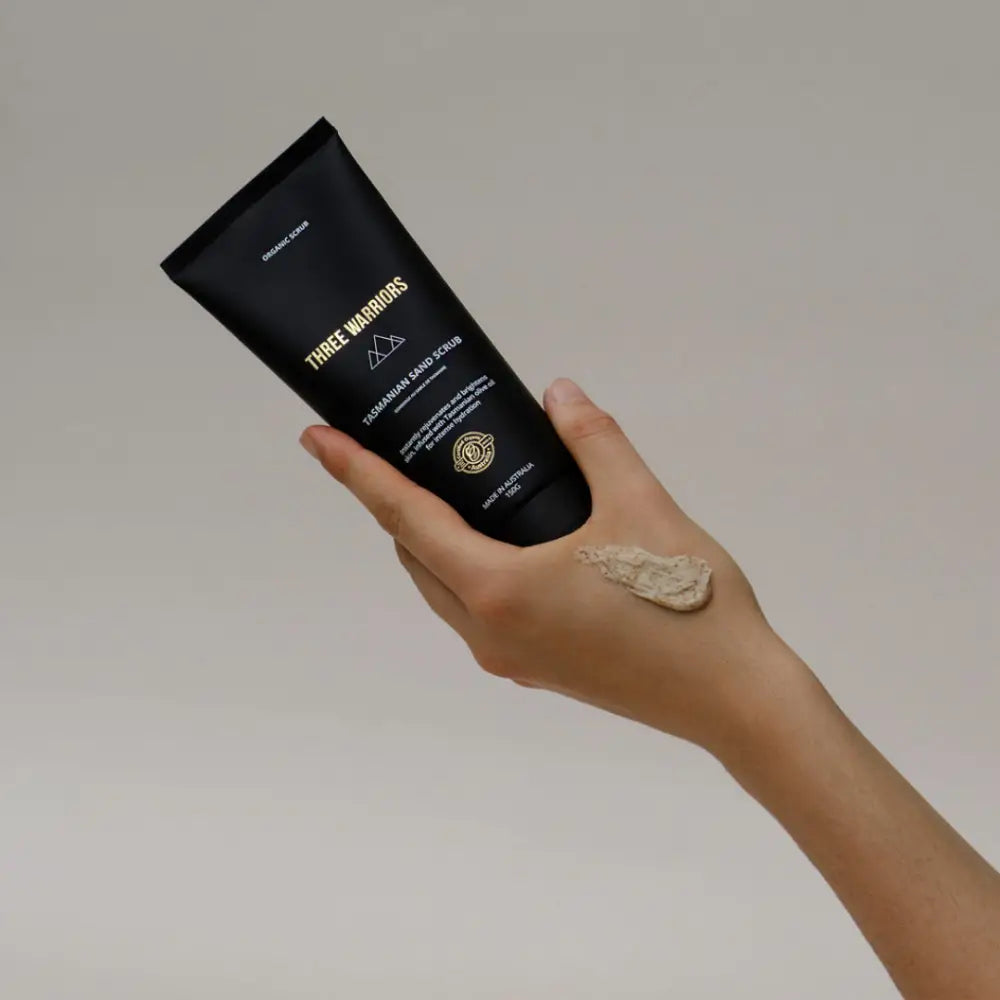 Black cosmetic tube with gold text being held by a hand.