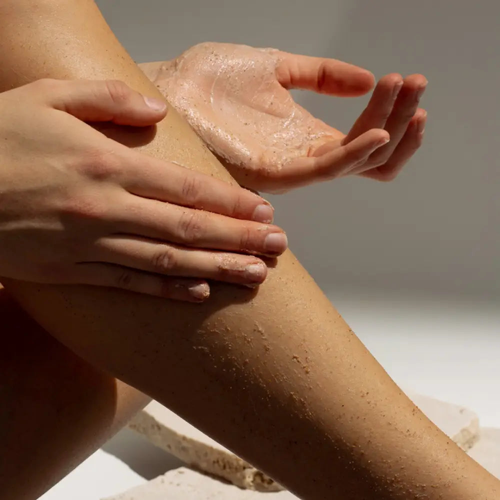 Hands applying moisturizer or lotion to wet skin.