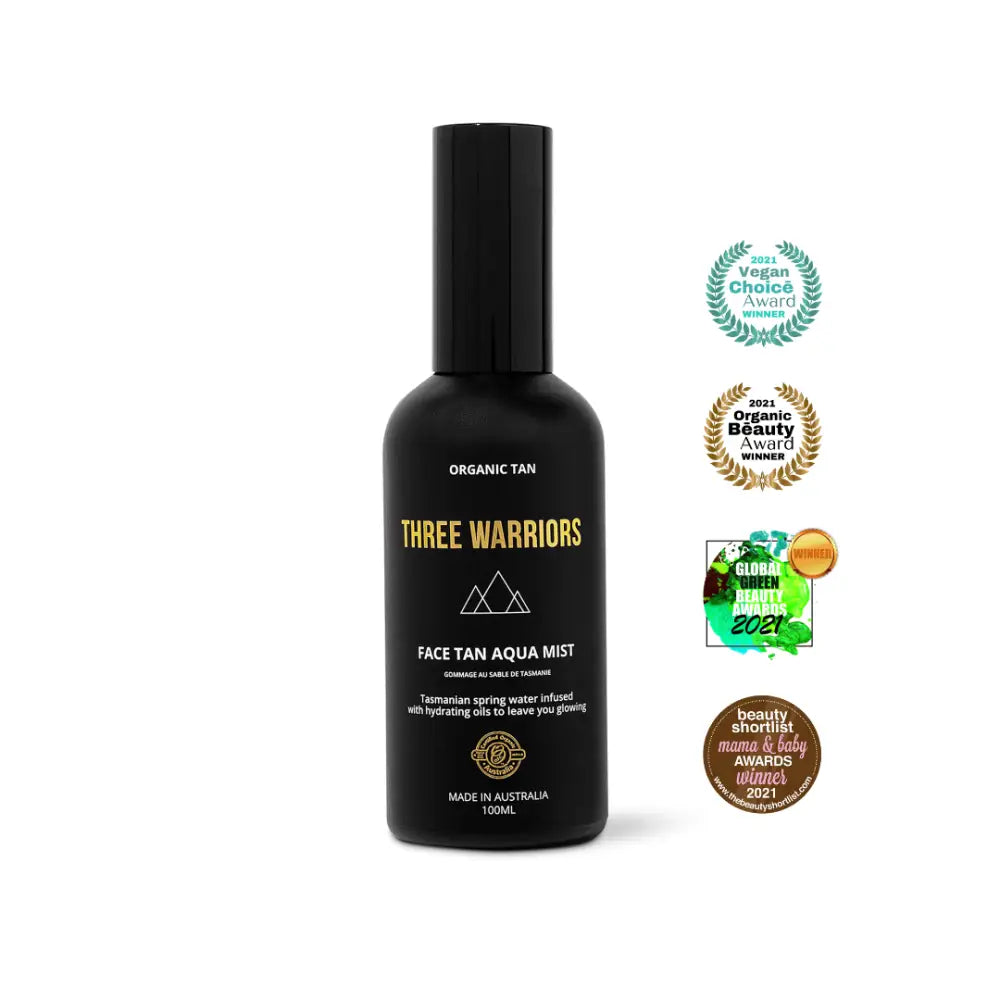 Black bottle of Three Warriors face tan aqua mist with award badges displayed beside it.