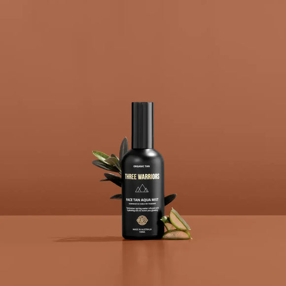 Black glass bottle with minimalist mountain logo and decorative leaves beside it.