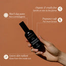 Black cosmetic bottle being held by a hand against a brown background with product benefit callouts.