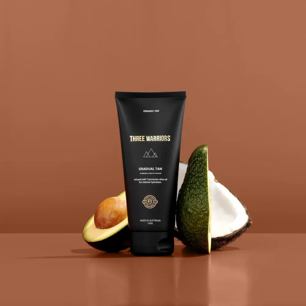 Black tube of Three Warriors branded product positioned between an avocado and coconut.