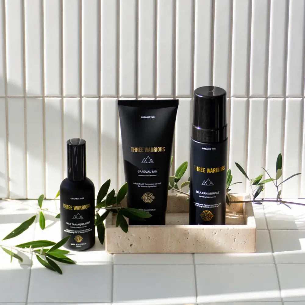 Three black skincare or grooming products arranged in a concrete or stone holder with olive branches.