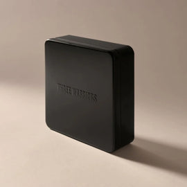 Black rectangular box with 'THREE WARRIORS' branding on a beige background