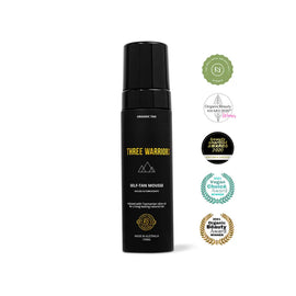 Black bottle of Three Warriors self-tanning mousse with award badges displayed alongside it.
