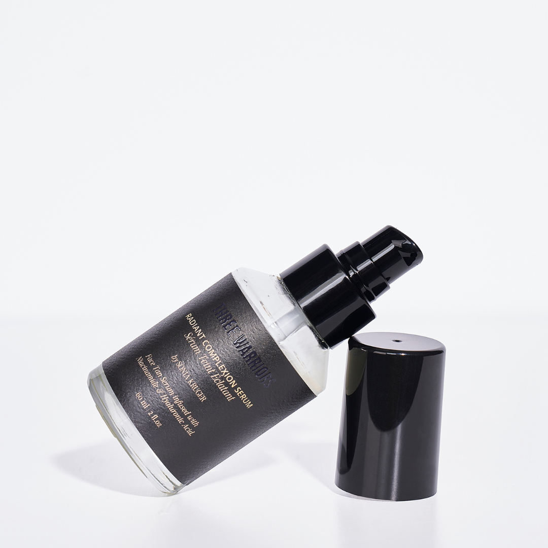 Three warriors radiant complexion serum by sonia kruger, with bottle leaning on lid sideways. The face tan serum, is an overnight skincare, with the ingredients of Hyaluronic Acid, Marine Collagen, and Niacinamide.